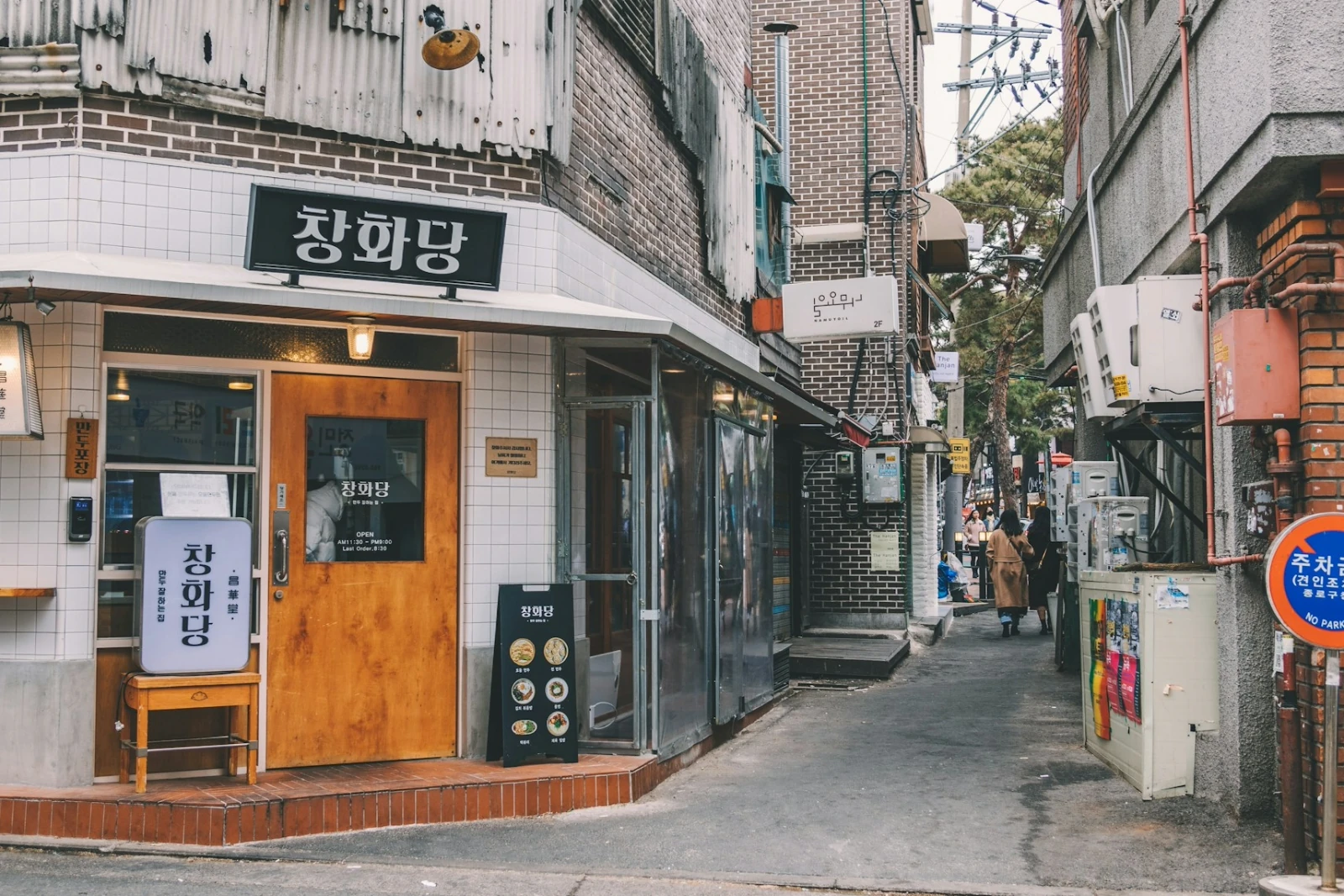 A neighborhood alley lined with restaurants and brick buildings in Seoul